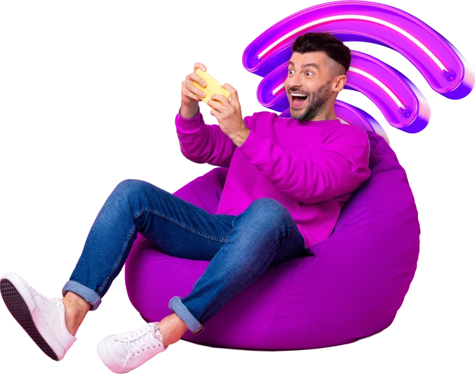 Man sitting on purple bean bag and playing game with wifi symbol.