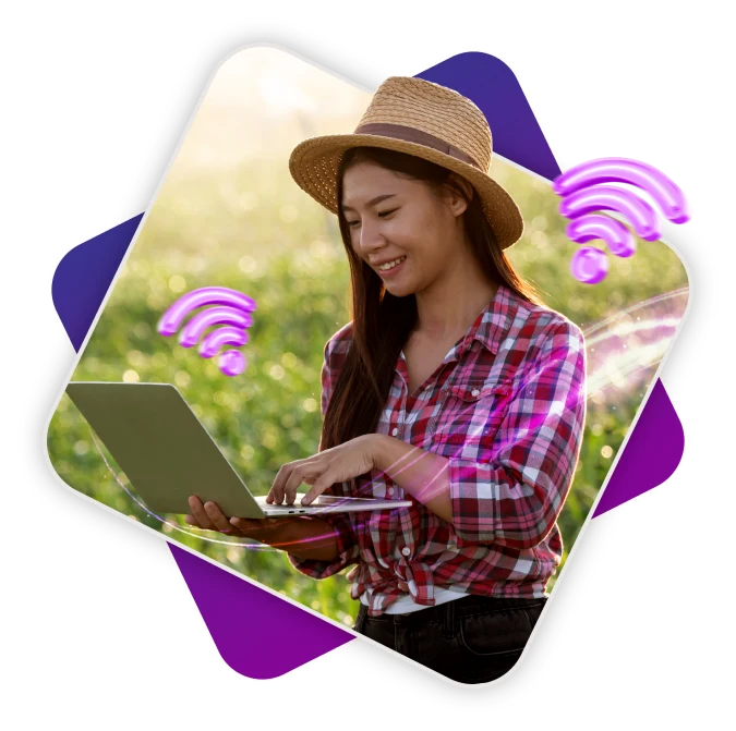 A woman in a hat and plaid shirt focused on her laptop, working diligently.